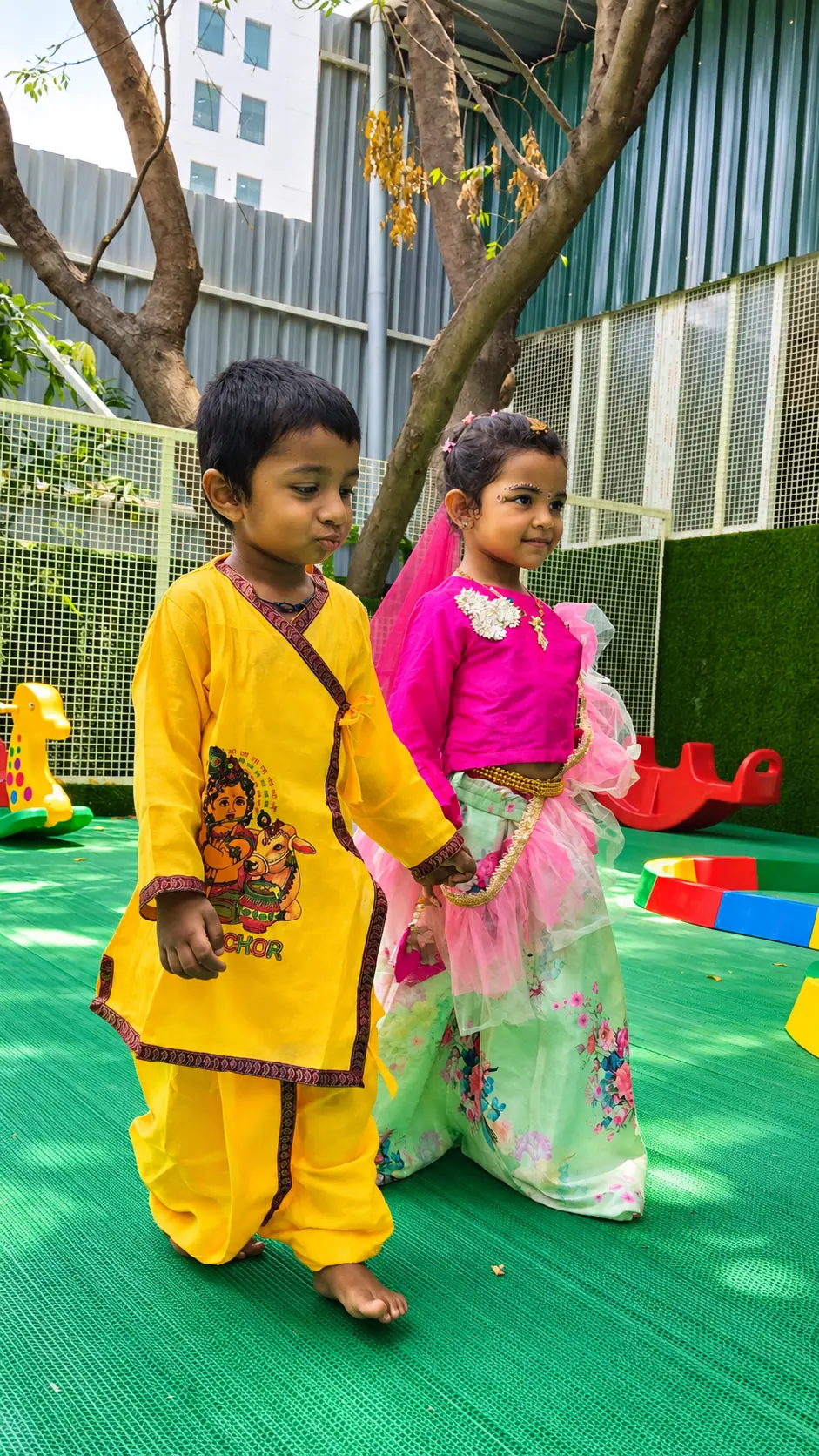 Two children in traditional Krishna and Radha festive dress playing together outdoors