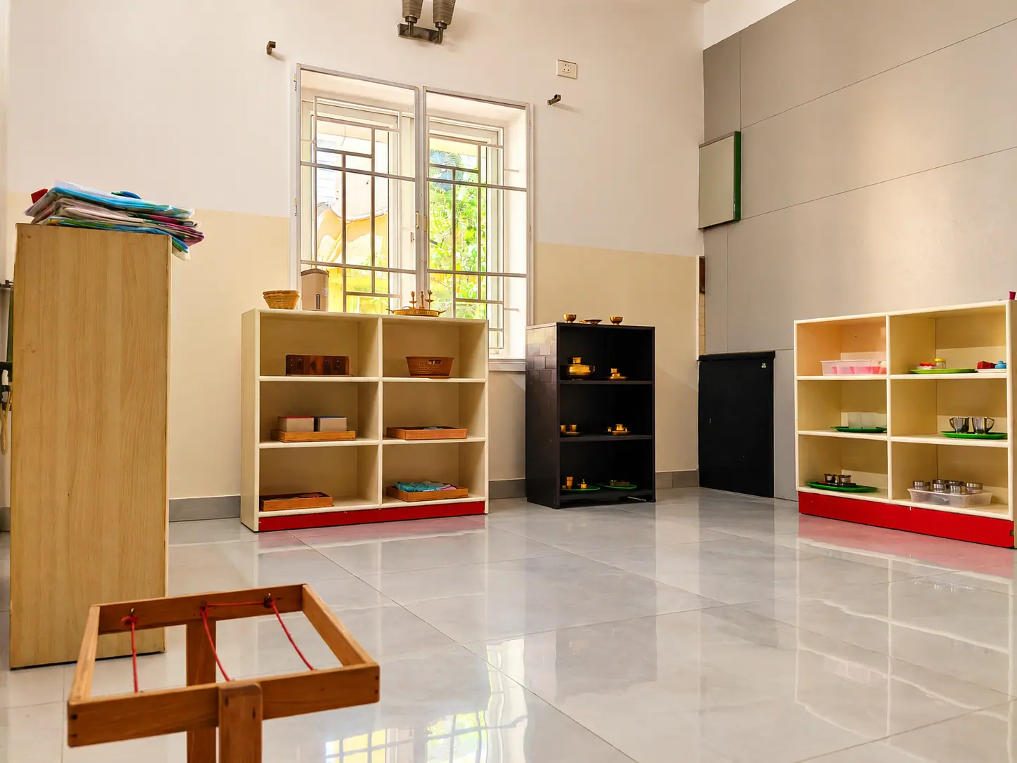 Wooden shelves of practical life and sensorial Montessori materials arranged for independent access