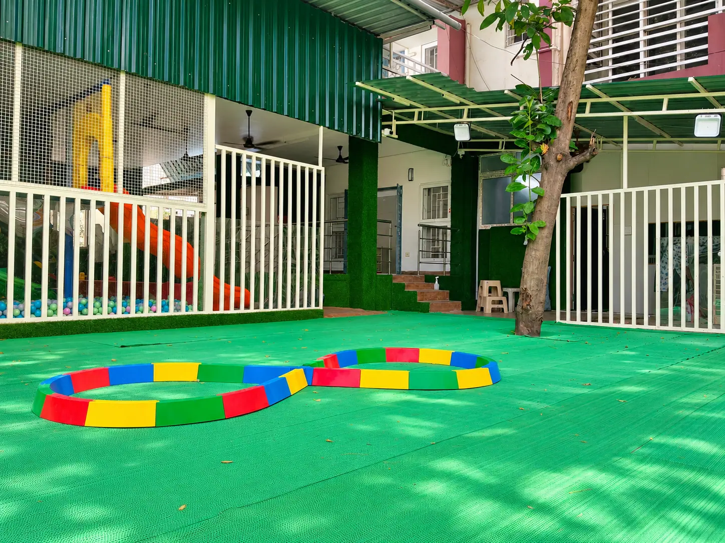 Covered outdoor play deck with a ball pit, orange slide, and colourful figure-8 balance track